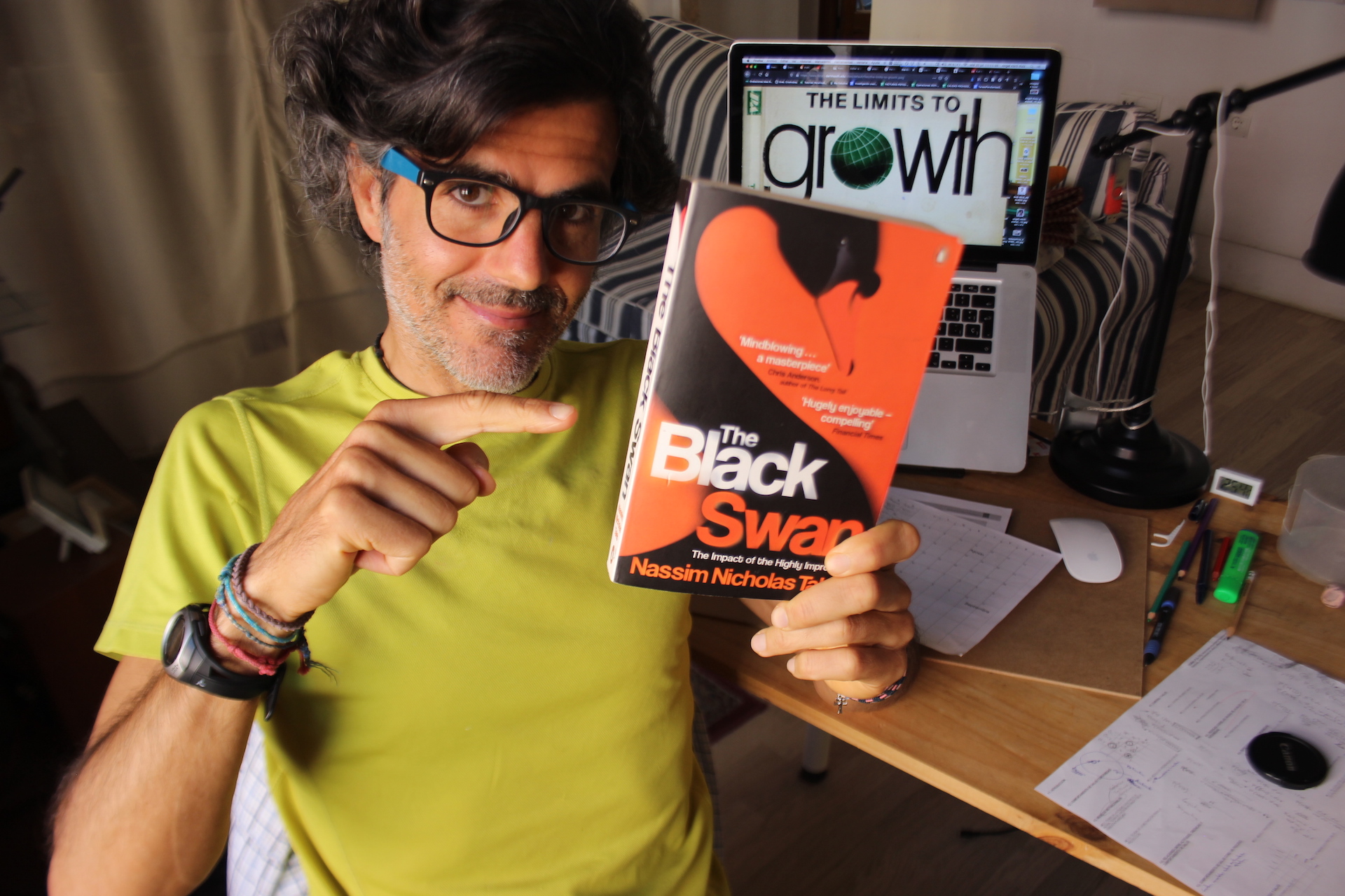Angel Abril Ruiz con el libro «The Black Swan» en la mano y la imagen del libro «The Limits To Growth» en el ordenador de fondo